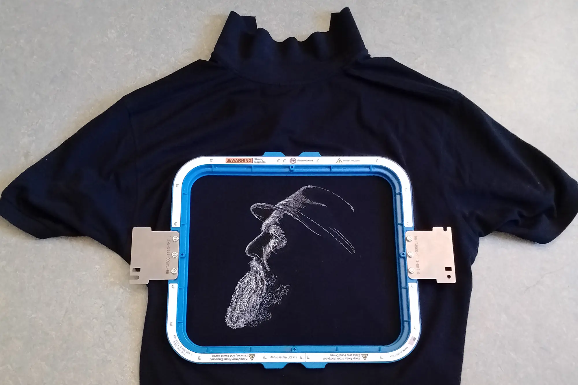 Stick eines Schwarz-Weiß Fotos auf einem schwarzen Poloshirt mit 23326 einzelnen Stichen